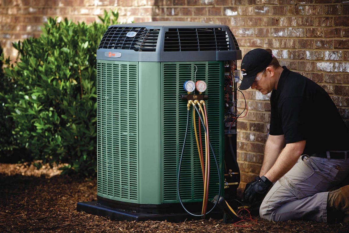 Technician servicing a residential air conditioner in OKC